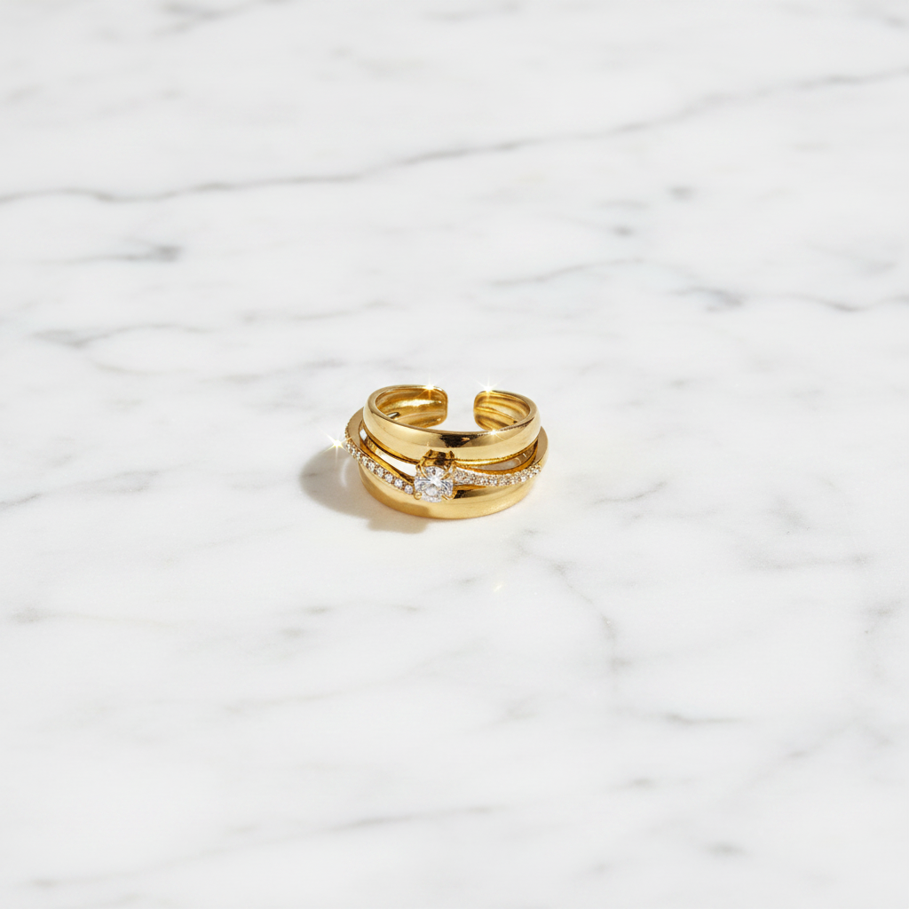 Flat lay bague dorée ornée de strass sur marbre blanc